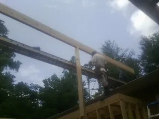 Carpenter setting a ridge beam over a new addition frame — Ice Dam Removal by Roofing Brothers in Gable