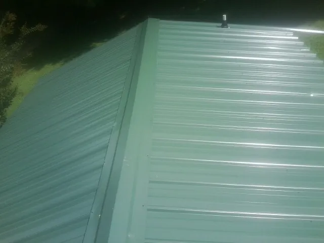 New green metal panels meeting at the ridge of a roof — Flat Roof Repair work by our crew in Gable
