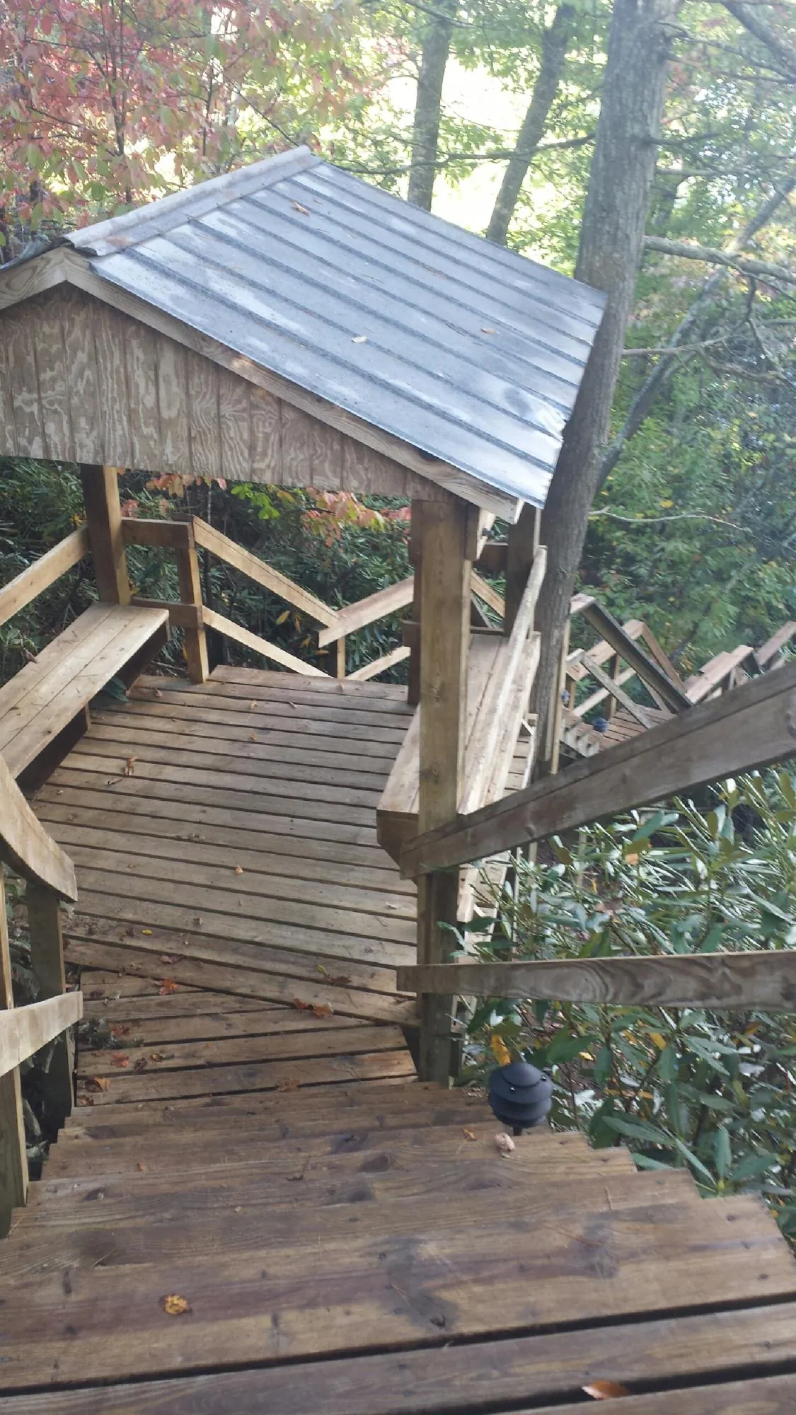 Metal roofed shelter over wooden steps on a wooded walkway — Skylight Repair & Installation work by our crew in Gable