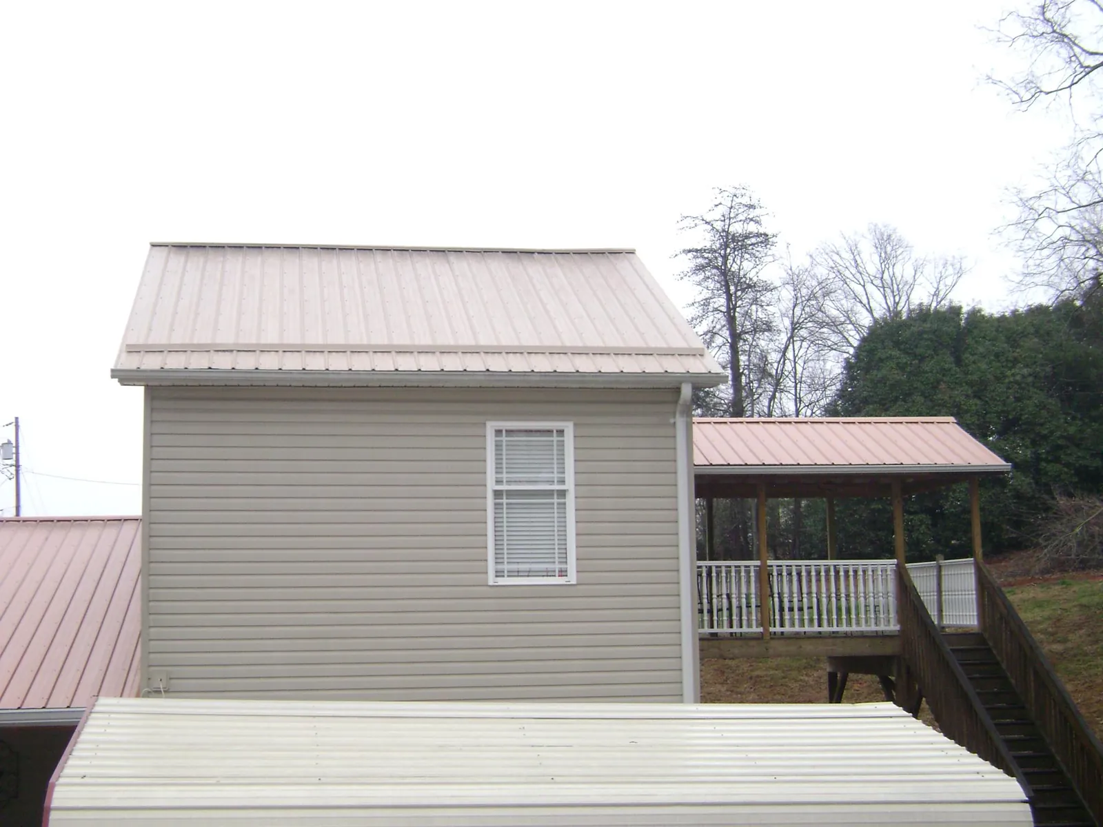 Tan metal roofs on a two story addition and attached porch, from a Roof Replacement job in Gable