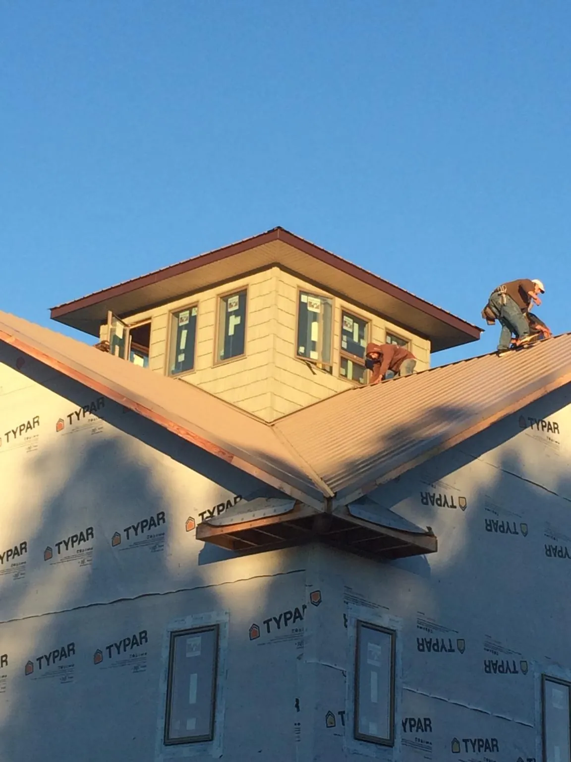 Roofers working around a rooftop cupola on a new metal roof at sunset — Roof Waterproofing in Gable by Roofing Brothers